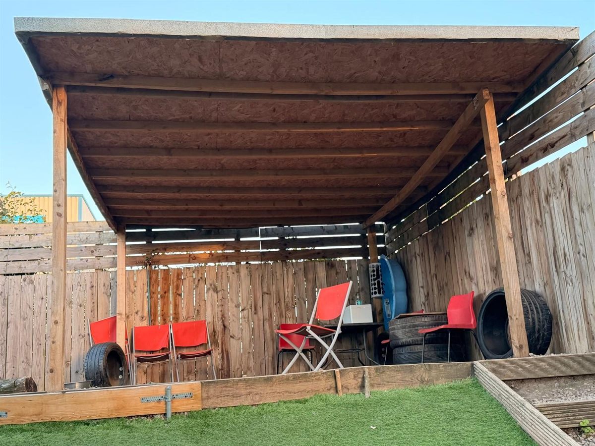 A close view of the covered shelter in the outdoor paddock, with seating and tyres